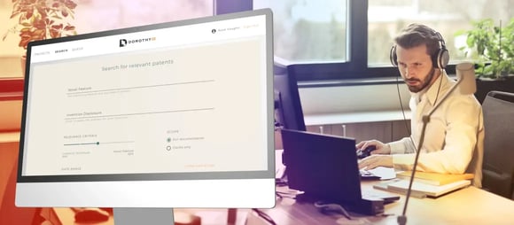 Professional wearing headphones working at a desk beside a monitor showing the Dorothy AI patent search screen, with fields for novel feature, invention disclosure and relevance criteria